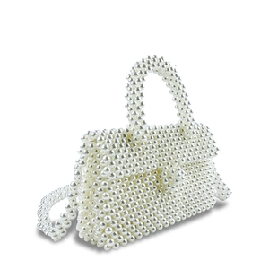 Detail of hand-woven white faux pearl beaded handbag with structured flap and top handle