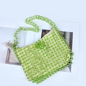 Detail of green beaded shoulder bag with satin lining placed on a decorative book