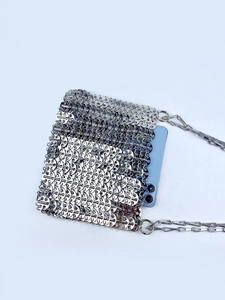 Macro view of silver metal plate evening bag interior showing smartphone for capacity
