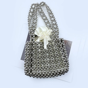 Detail of silver beaded handbag with a white satin drawstring inner bag and bow accent