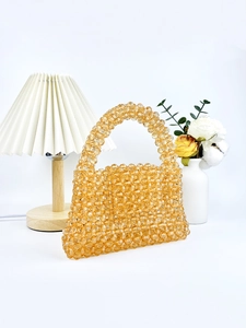 Sac à main artisanal en perles d'acrylique ambré sur fond décoratif minimaliste