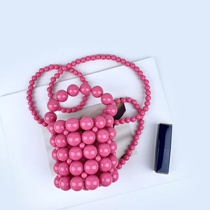Detailed close-up of pink beaded bucket bag with lipstick and stylish accessories
