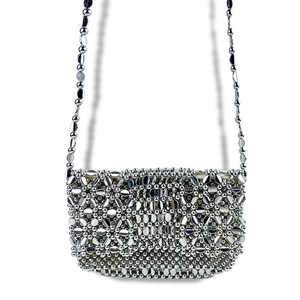 Detail of silver metallic beaded crossbody bag with handmade woven floral hollow design