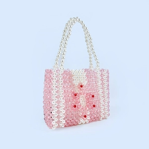 Vue détaillée du sac en perles acryliques roses fait main avec un motif floral blanc