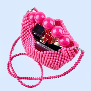 Detail of pink beaded handbag showing interior space with cosmetics and large bead handle