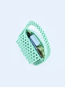 Top-down view of mint green beaded handbag interior showing small makeup items storage