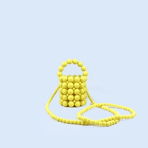 Detail of yellow handmade beaded bucket bag with shiny acrylic pearls and long shoulder strap