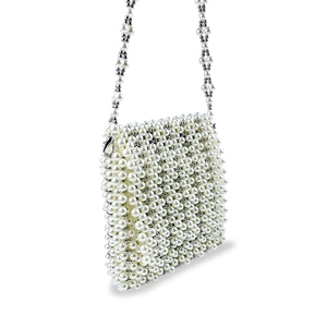 Détail d'un sac bandoulière fait main en perles blanches avec des fermoirs mousquetons argent