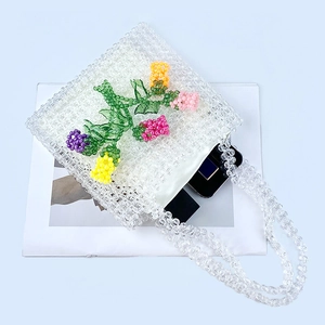 Detail of handmade acrylic beaded bag featuring 3D colorful floral patterns on a white base