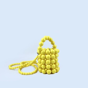 Detail of bright yellow handmade beaded bucket bag with smooth round pearls and strap