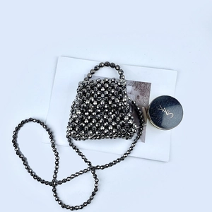 Detailed close-up of a handmade black beaded crossbody bag with metallic reflective beads