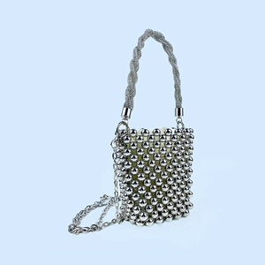 Detailed close-up of a silver beaded bucket bag featuring a woven handle and chain strap