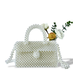 Detail showing handcrafted white faux pearl weave and spherical clasp on the elegant handbag
