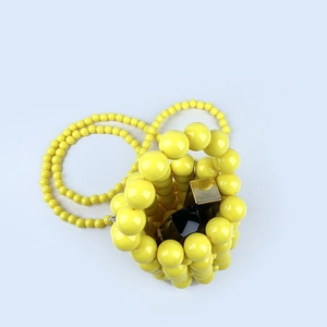 Detail view of yellow handmade beaded bucket bag showing mini capacity for a lipstick