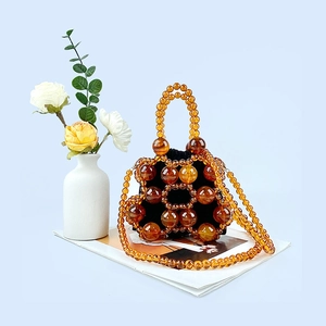 Detail of amber beaded bucket bag with drawstring pouch on a light blue background