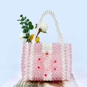 Détail du sac perlé fait main avec motifs floraux et anse en perles sur fond bleu clair