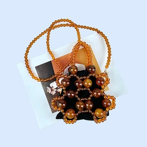 Close-up of amber beaded bucket bag with black drawstring liner and shell textures