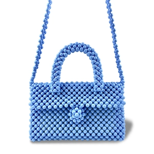 Detail of light blue handmade beaded bag showing crystal texture and floral bead accent