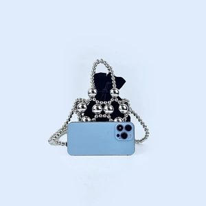 Macro shot of silver beaded mini handbag with black velvet drawstring pouch and phone reference