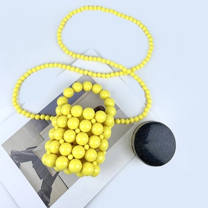 Detailed close-up of handmade yellow beaded mini bucket bag with textured pearl weaving