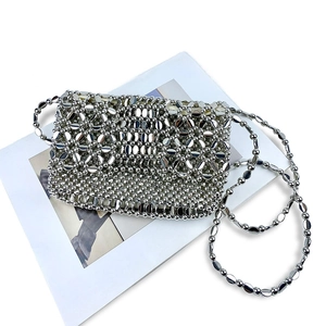 Detail of silver handcrafted woven beaded crossbody bag with metallic floral hollow design