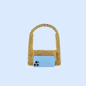 Comparaison de taille détaillée d'un sac perlé doré à côté d'un smartphone
