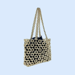 Detail of handmade gold beaded shoulder bag with shiny hollow grid and blue satin inner pouch