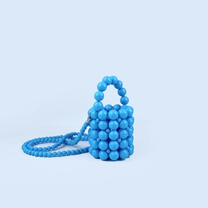 Macro detail of hand-woven bright blue beaded bucket bag with mini crossbody strap