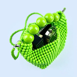 Detail of green handmade beaded handbag showing interior space with cosmetics
