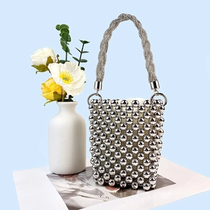 Close-up of silver beaded bucket bag with twisted metal handle and shiny finish