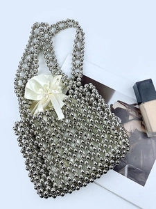 Handmade silver beaded square tote bag with interior drawstring pouch on fashion magazine background