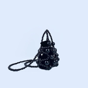 Detail of handmade black beaded handbag with glossy finish and velvet drawstring liner