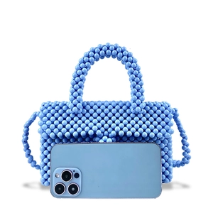 Handmade light blue beaded handbag with crossbody strap shown next to a smartphone