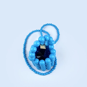 Detailed view of hand-woven electric blue beaded bucket bag with shiny pearl-like texture