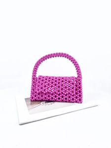 Detailed view of handmade beaded handbag with pink resin beads on a white magazine