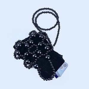 Macro shot of black beaded mini handbag with soft velvet drawstring inner pouch detail