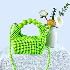 Detailed close-up of bright green handmade beaded handbag with oversized sphere handle