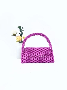 Detail of handcrafted purple beaded handbag with intricate woven mesh and rounded handle