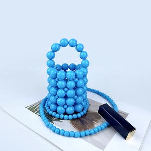Detailed view of a bright blue handmade beaded bucket bag with a pearl strap and circular handle