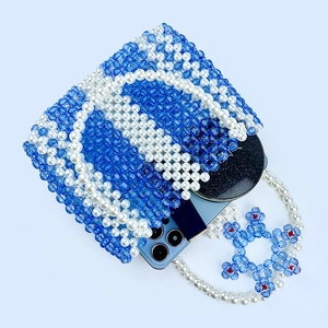 Détail du sac à main perlé à la main montrant l'espace pour téléphone et miroir