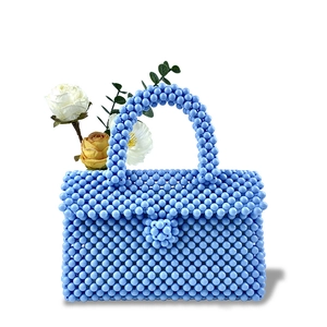 Close-up of handmade light blue beaded handbag with round acrylic beads and woven handle