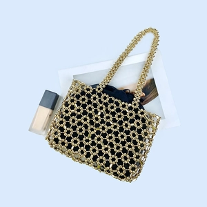 Detailed view of golden hand-woven bead mesh tote with a black drawstring pouch