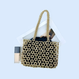 Detail of handmade gold beaded shoulder bag with hollow geometric pattern and black drawstring liner