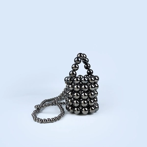 Detail of dark grey metallic beaded bucket bag with long crossbody chain and top handle