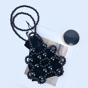 Macro shot of black handmade beaded mini bag with plush drawstring liner and long strap