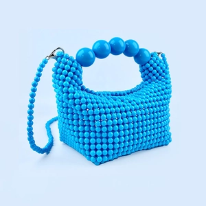 Detail of bright blue beaded handbag showing woven texture and matching bead strap
