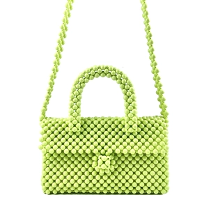 Detail of light green beaded handbag with handmade weave and flower shaped closure button