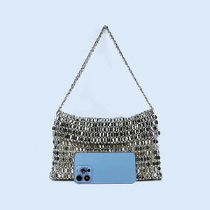 Detail view of silver sequin handmade woven bag showing size next to a smartphone