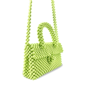 Detail of neon green beaded crossbody bag featuring a woven flap and top handle design
