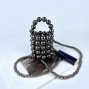 Macro view of a dark grey handmade beaded bucket bag featuring a high-gloss metallic finish